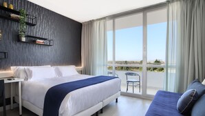 A modern bedroom with a large bed, a desk, and a balcony with a view. - Hotel Luze El Villa (Castejón)
