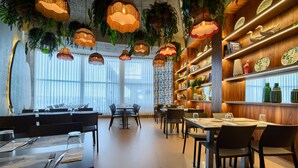 A restaurant with multiple dining tables, hanging pendant lights, and shelves with decorative items. - Hotel Luze El Villa (Castejón)
