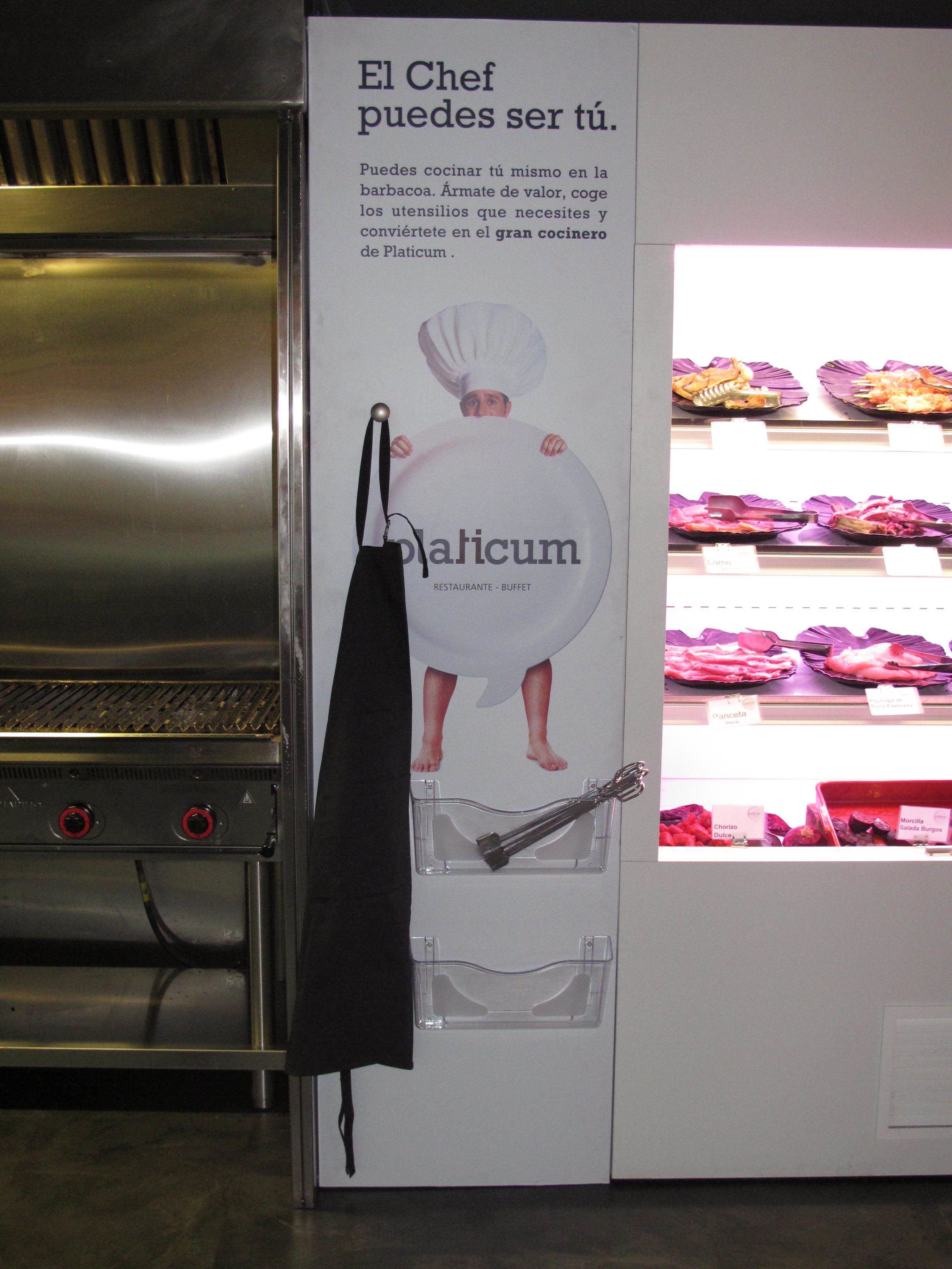 Una zona de cocina con una campana de acero inoxidable y un delantal negro colgado en la pared.