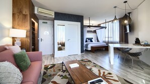 A modern hotel room with a sofa, a coffee table, a bed, a desk, and a TV. - Hotel Luze El Villa (Castejón)