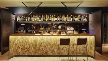 Un bar con diseño de madera, estantes con botellas de licores y dos taburetes.
