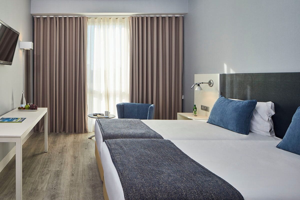 Una habitación de hotel con una cama grande, un escritorio, una silla y una televisión.
