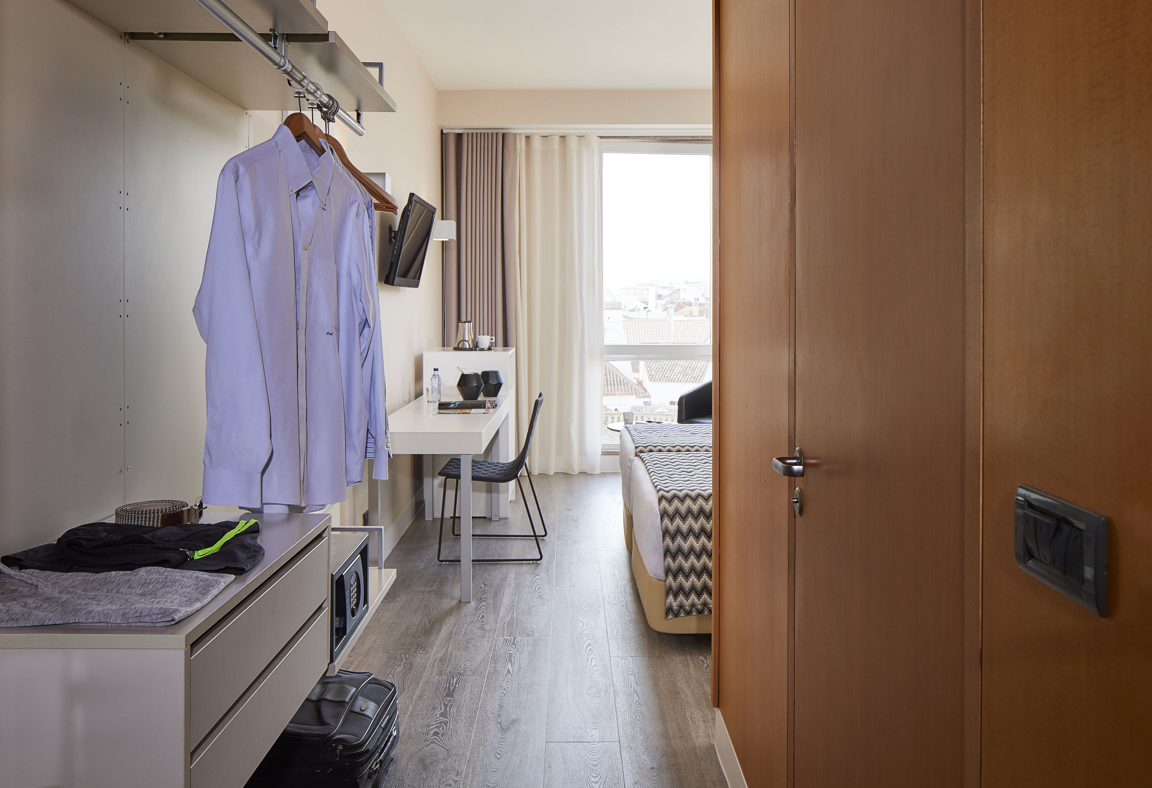 Een hotelkamer met een bed, een bureau, een stoel, een kledingkast en een televisietoestel.