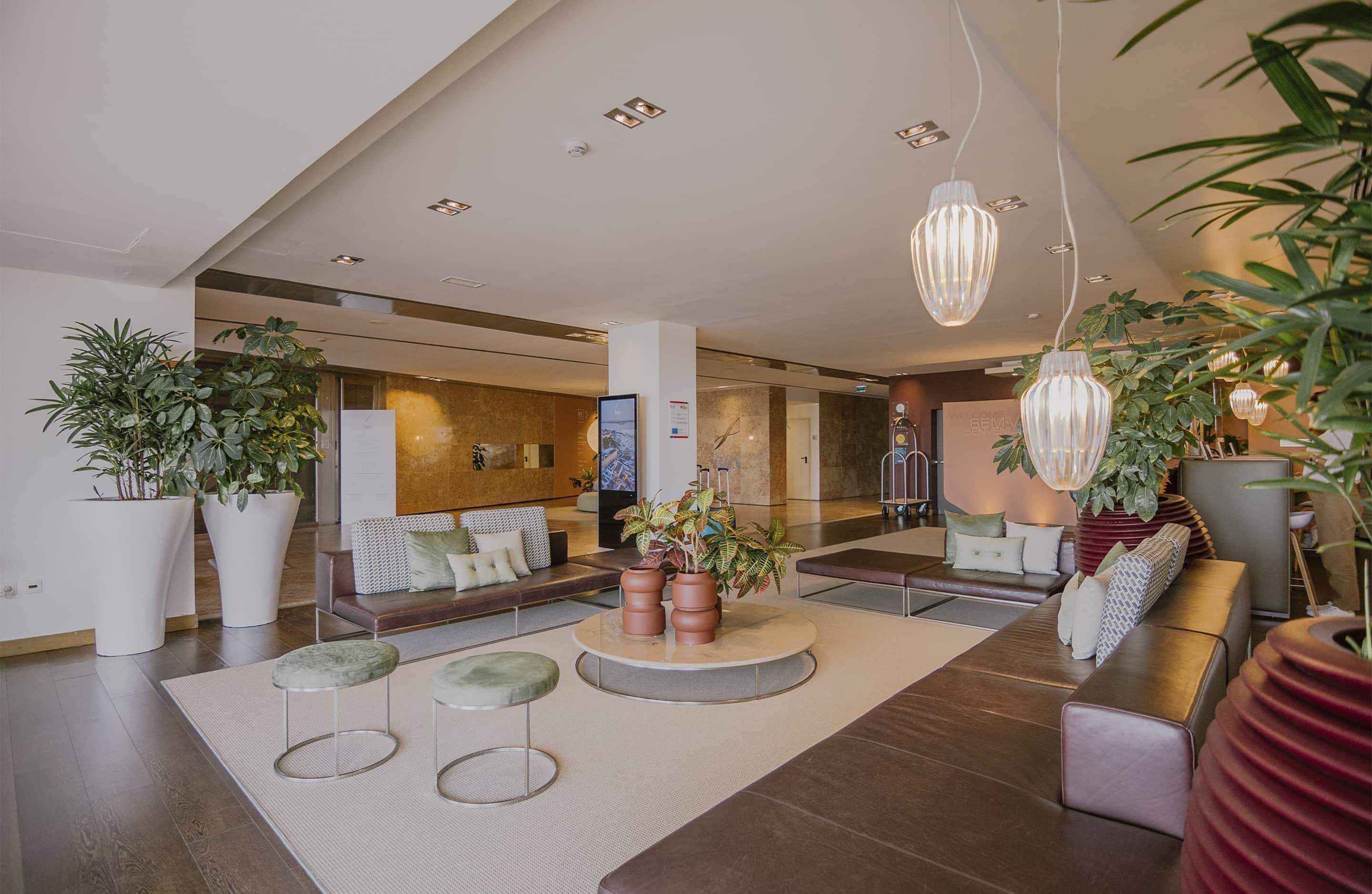 A spacious lobby with seating areas, potted plants, and modern lighting fixtures.
