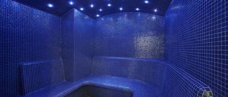 A blue-tiled room with a curved bench and a small table.