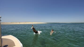 A boat with a sandy beach and calm water in the background.