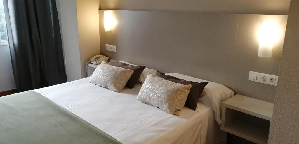 A hotel room with a bed, bedside tables, and a telephone.