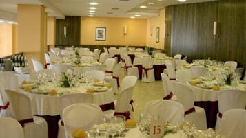 A banquet hall with round tables, white tablecloths, and red sashes on chairs.
