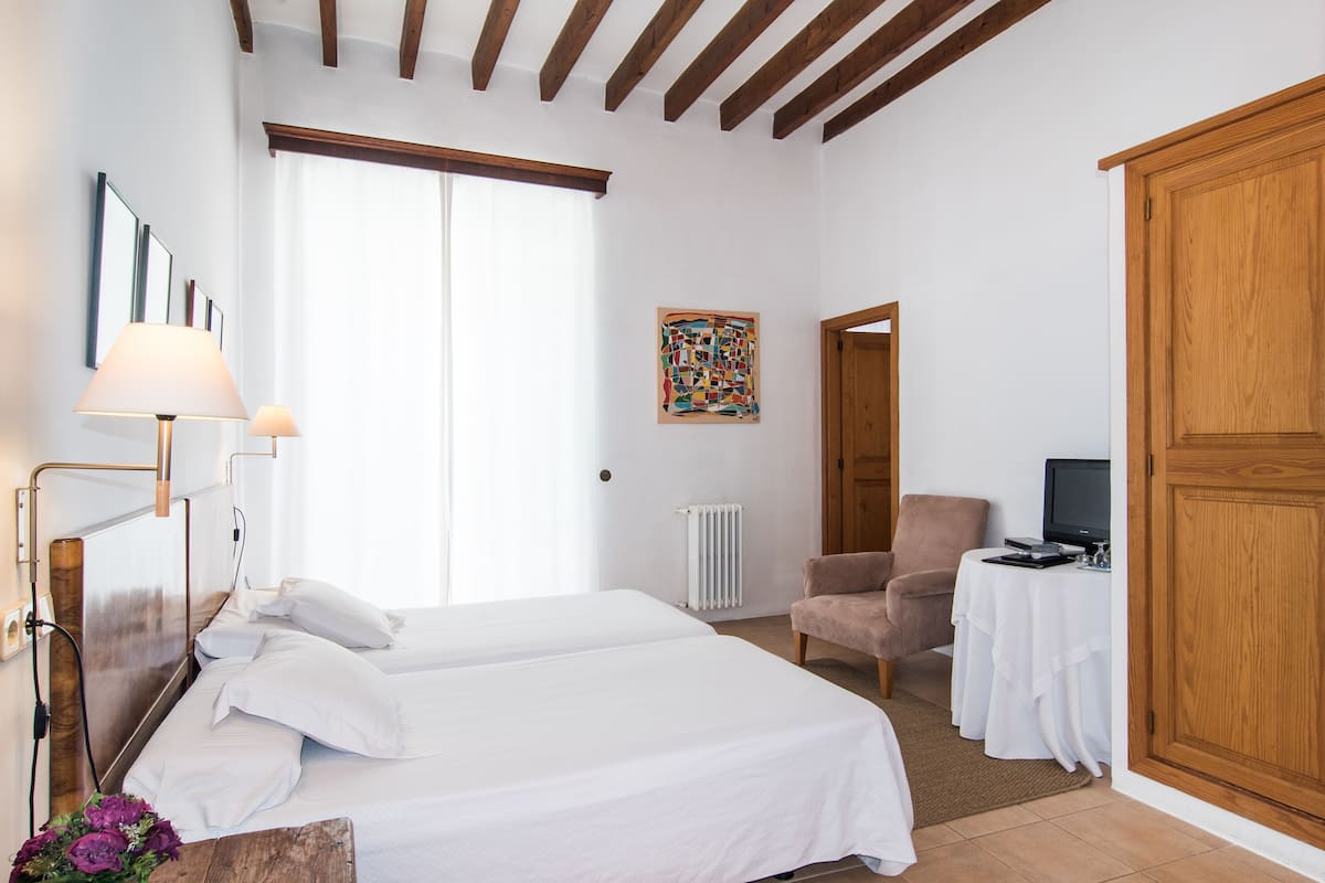 Habitación de hotel con dos camas, un escritorio con computadora, una silla y un armario grande.