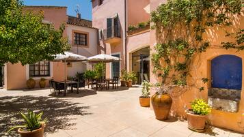 Un espace extérieur aménagé en terrasse, avec des tables, des chaises, des plantes en pot et des parasols.