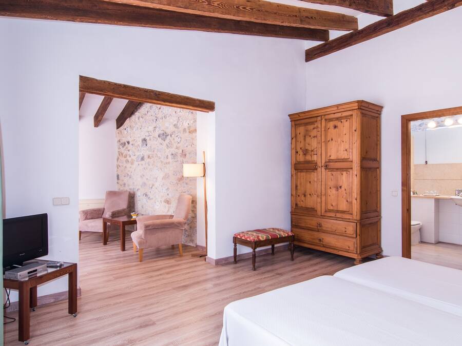 A room with a bed, wooden wardrobe, television, and a small table.