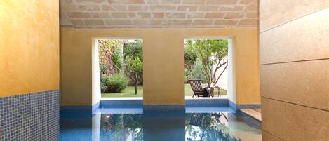 Una piscina con vistas a un jardín y una silla.