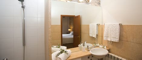 Un baño con ducha, lavamanos y espejo.