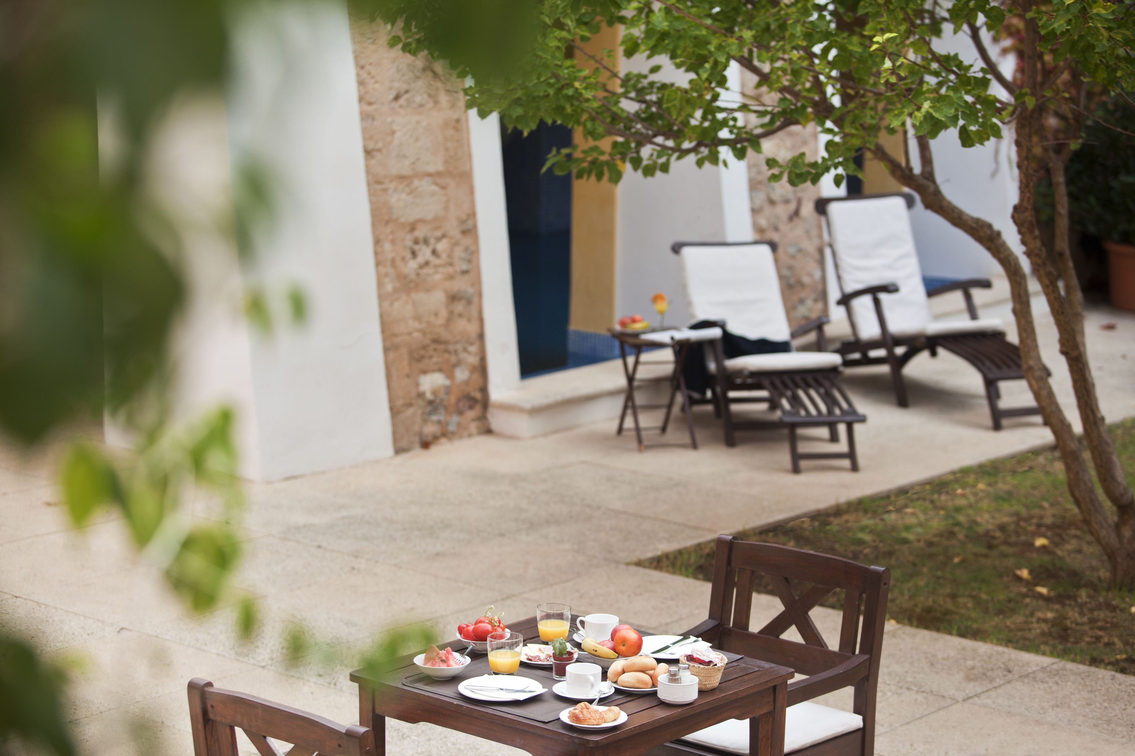 An outdoor dining area with a table set for breakfast, including plates, cups, and a basket.