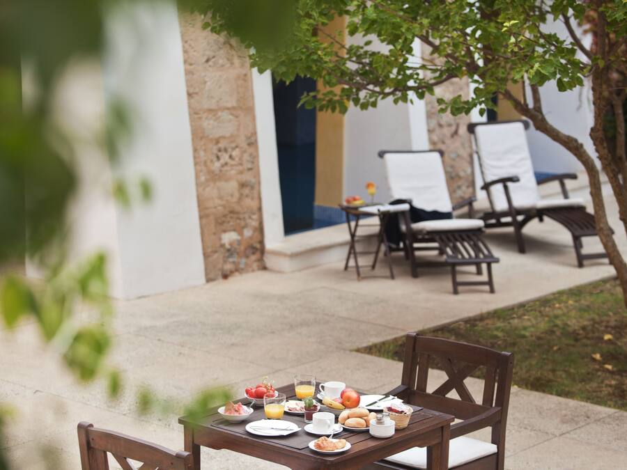 An outdoor dining area with a table set for breakfast, including plates, cups, and a basket.