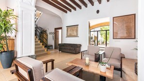 A spacious living area with a staircase, a sofa, a coffee table, and a potted plant. -  Hotel Can Moragues (Arta)