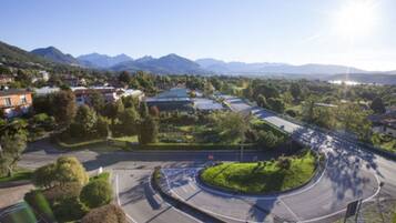 A roundabout with a road leading to a building complex surrounded by greenery and mountains.