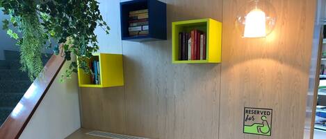 A modern reading nook with a built-in desk, two colorful bookshelves, and a 'Reserved for' sign on the wall.