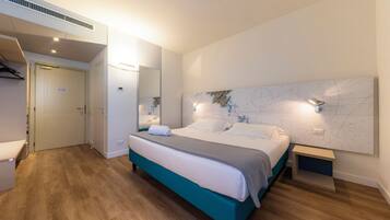 A modern bedroom with a bed, bedside tables, a mirror, and a map on the wall.