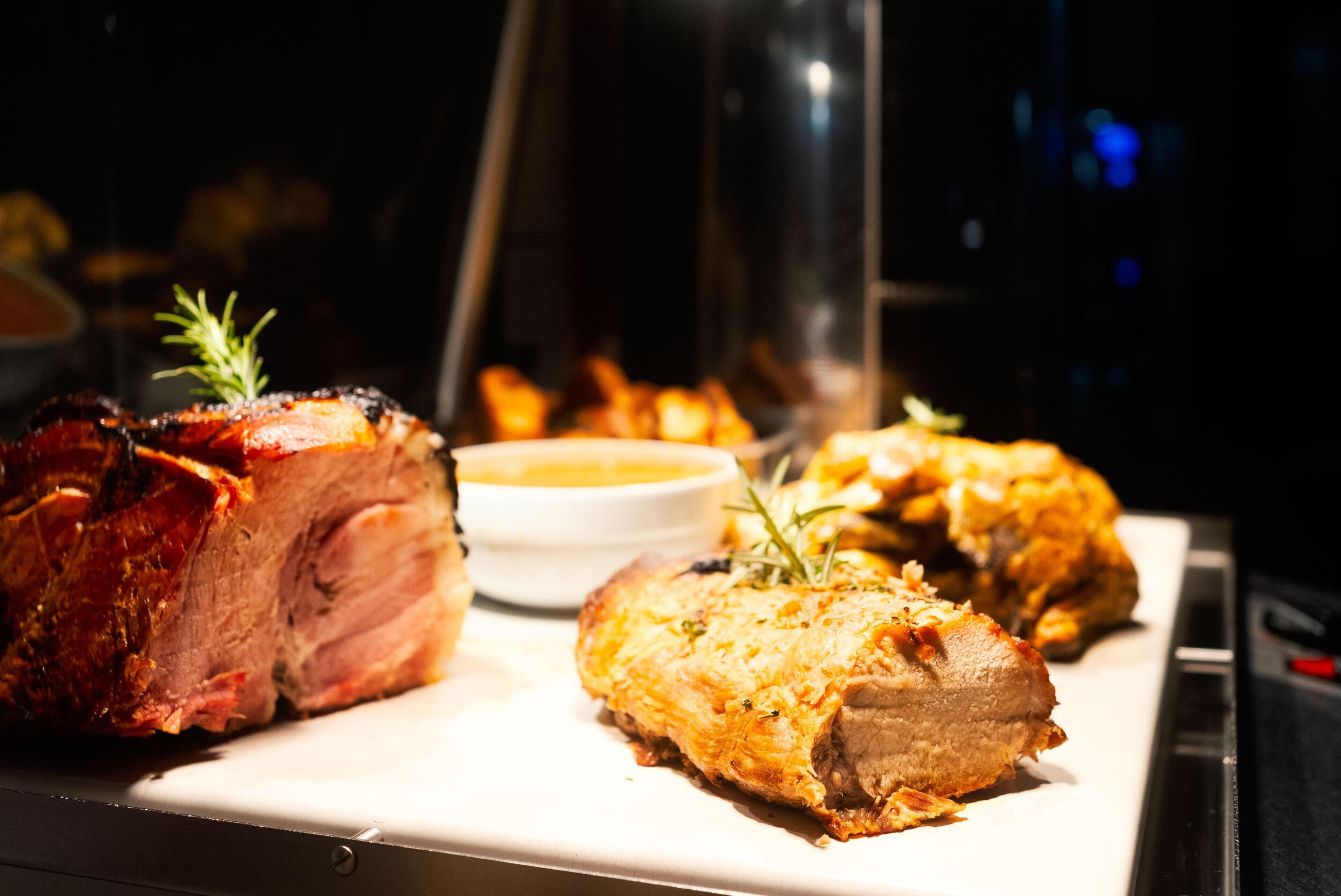 Un plat de viande rôtie, accompagné d’une sauce et servi avec une petite portion de cette même sauce dans un bol.