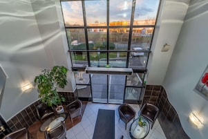 Habitación de hotel moderna con un gran ventanal, una planta en maceta y un rincón de estar con sillas y una mesa.