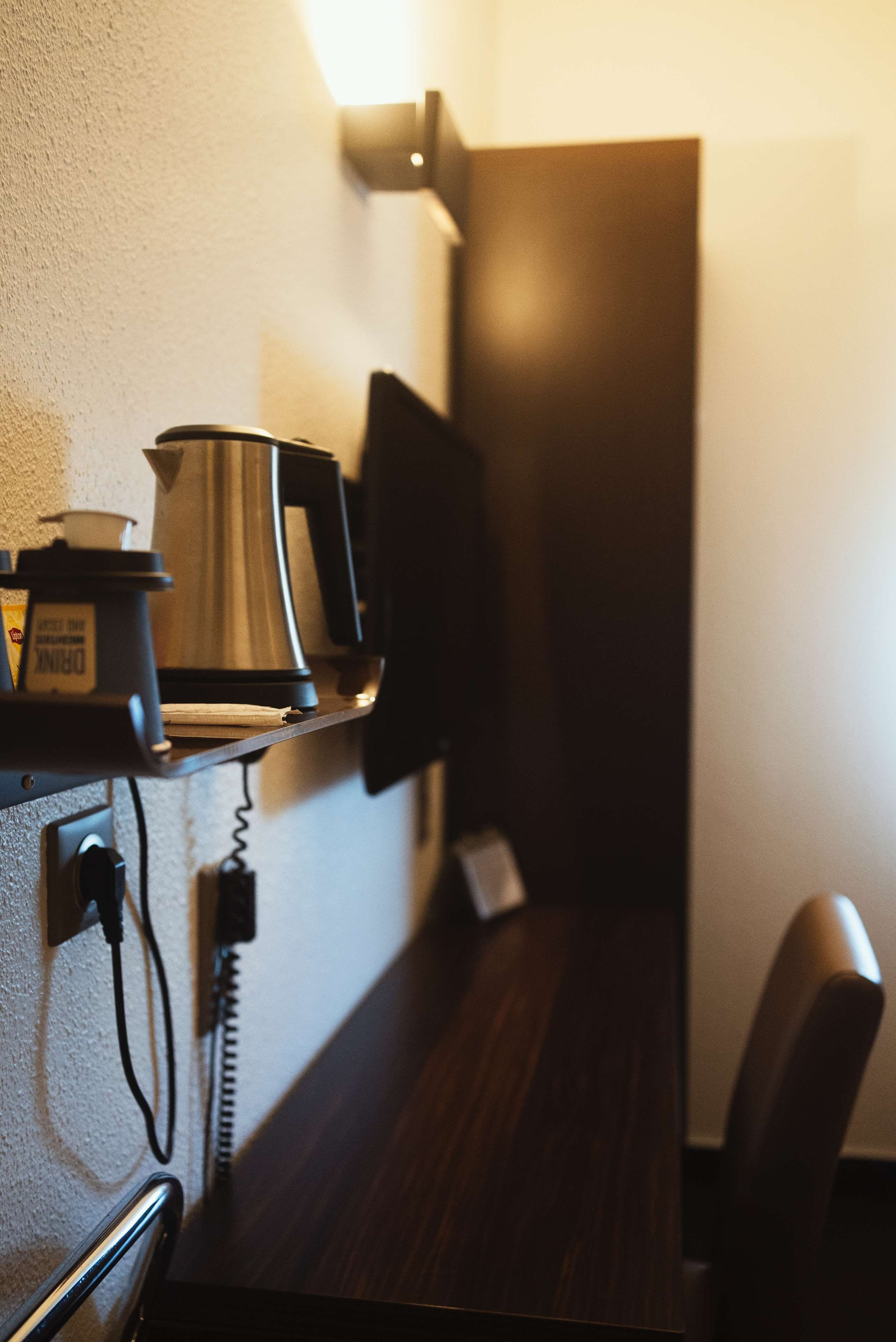 Une petite cuisine équipée d’une machine à café, d’une bouilloire et d’un téléphone posé sur une étagère.
