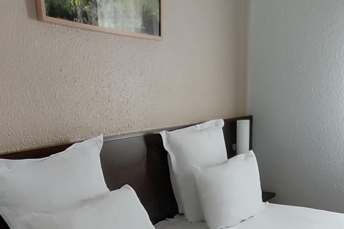 A hotel room with two beds, a large window, and a framed picture on the wall.