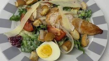 Un plato de comida con ensalada, pollo, huevos y cubitos de pan.
