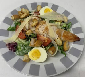 Ein Teller mit Essen, darunter Salat, Hähnchen, Eier und Croutons.