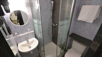 A bathroom with a glass-enclosed shower, a sink, and a toilet.