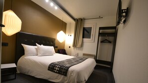 A hotel room with a bed, bedside table, lamp, and a mirror.