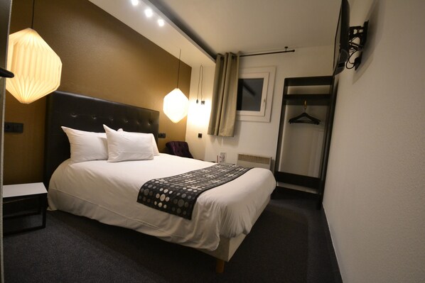 Ein Hotelzimmer mit Bett, Nachttisch, Lampe und Spiegel.