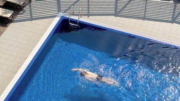 Una piscina amb un nedador, gandules i un solàrium reial.