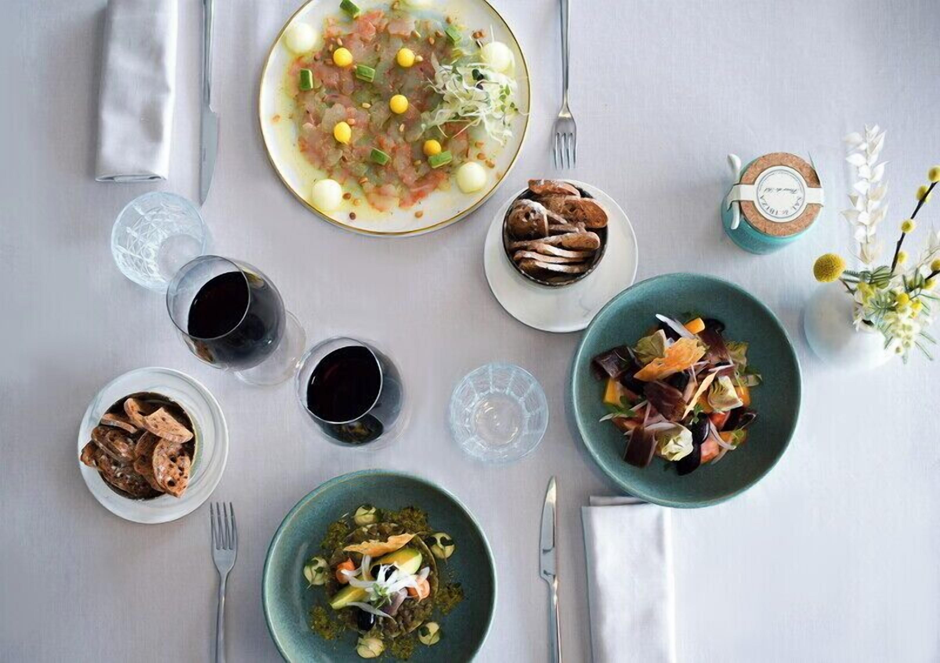 A dining table with various dishes, glasses, and cutlery.