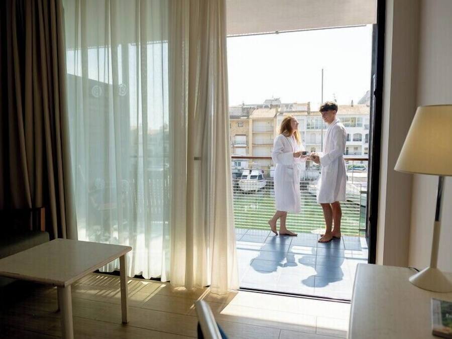 Une chambre d’hôtel avec un balcon, une table et une lampe.