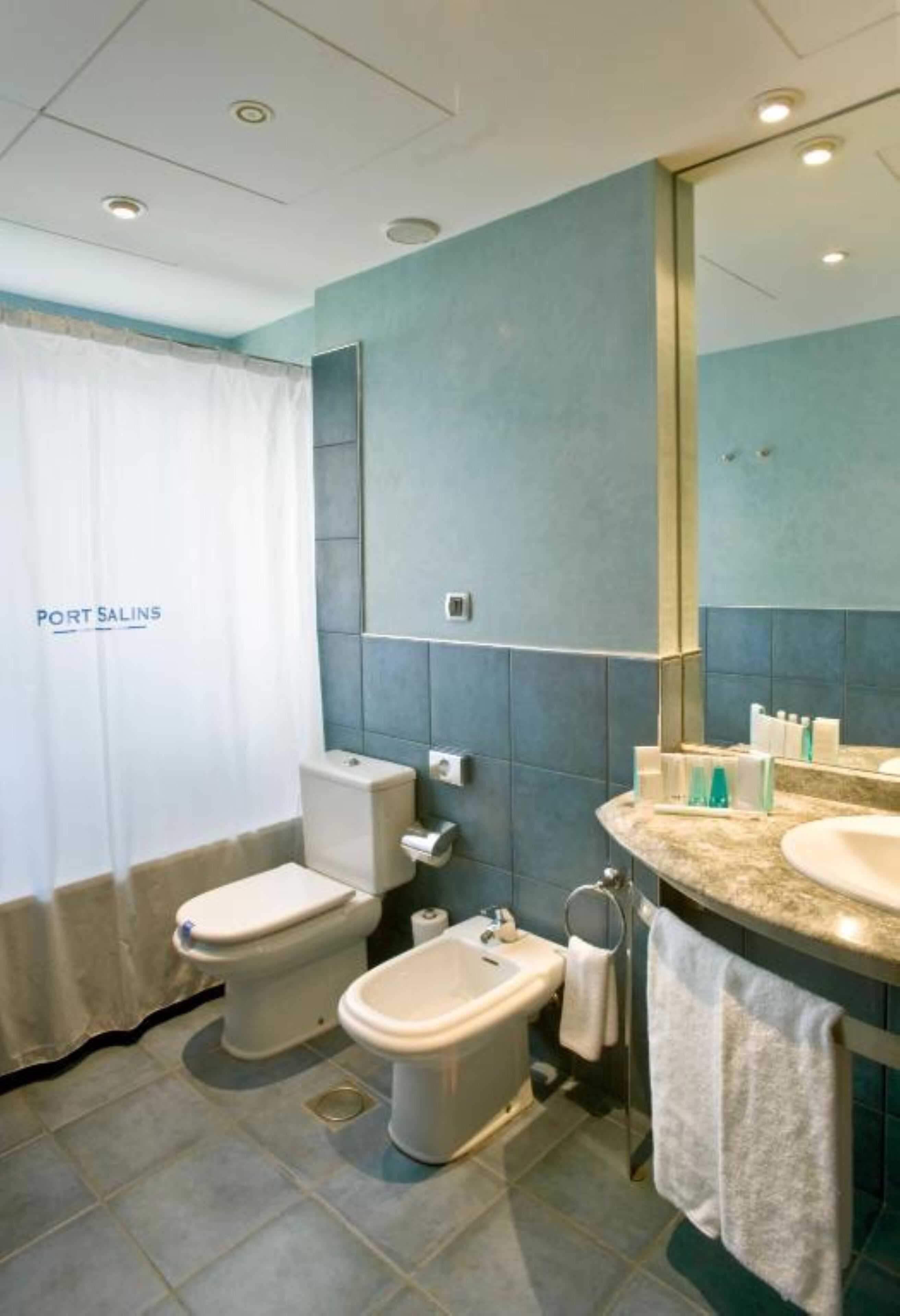 A bathroom with a toilet, bidet, and sink, with a mirror above the sink.