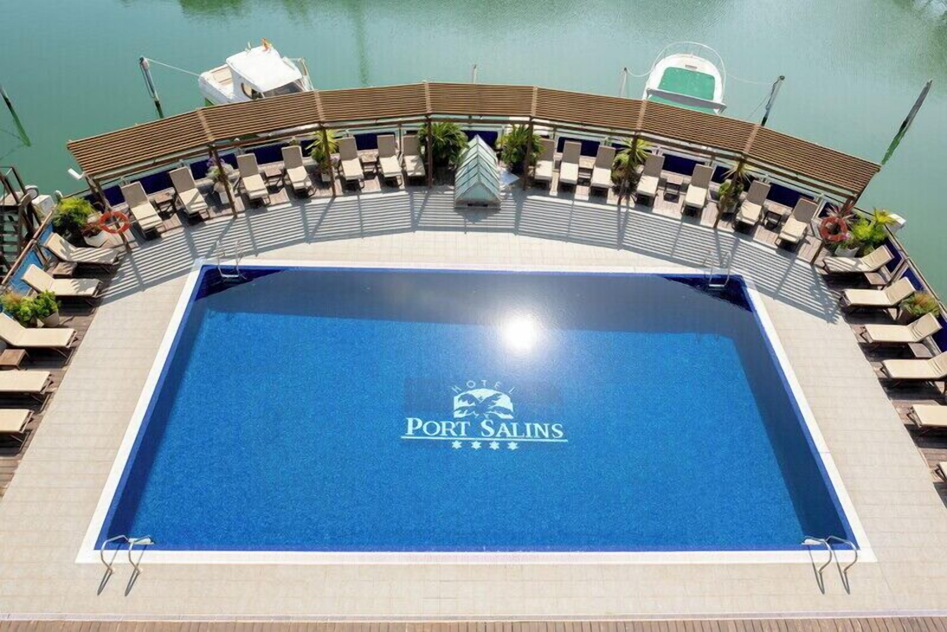 Un espace piscine avec des chaises longues et un panneau indiquant « Port Salins ».