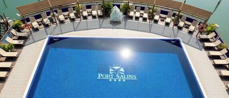Zona de piscina con sillas de descanso y un cartel que dice 'Port Salins'.
