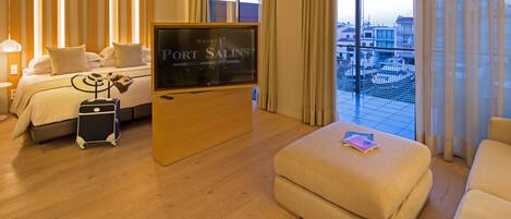 A hotel room with a bed, a TV, a suitcase, and a balcony with a view.