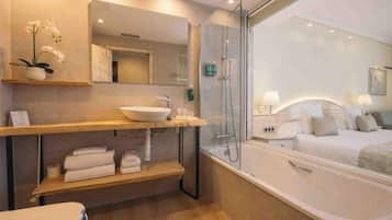 Een moderne badkamer met een douchecabine van glas, een ruim bad en een wastafelmeubel met een wastafel en spiegel.