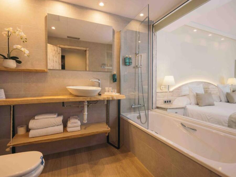 Een moderne badkamer met een douchecabine van glas, een ruim bad en een wastafelmeubel met een wastafel en spiegel.