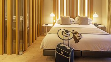 A hotel room with a large bed, bedside tables, a suitcase, and a hat on the bed.