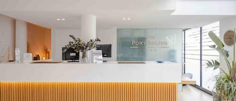 A modern hotel reception desk with a glass partition displaying the name 'Hotel Port Salins'.