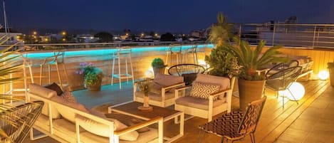 A rooftop bar with seating and a pool.