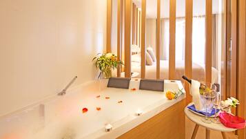 A modern bathroom with a bathtub, a small table with a bottle, glasses, and a red bag.