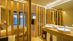 A modern hotel room with a large bed, a double sink, and a large mirror. - Hotel Port Salins by Pierre & Vacances (Castello d'Empuries)