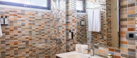 A bathroom with a tiled shower, a sink with a mirror, and a window above the sink.