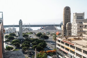 Un paisaje urbano con un monumento destacado, un edificio alto y una marina con barcos.