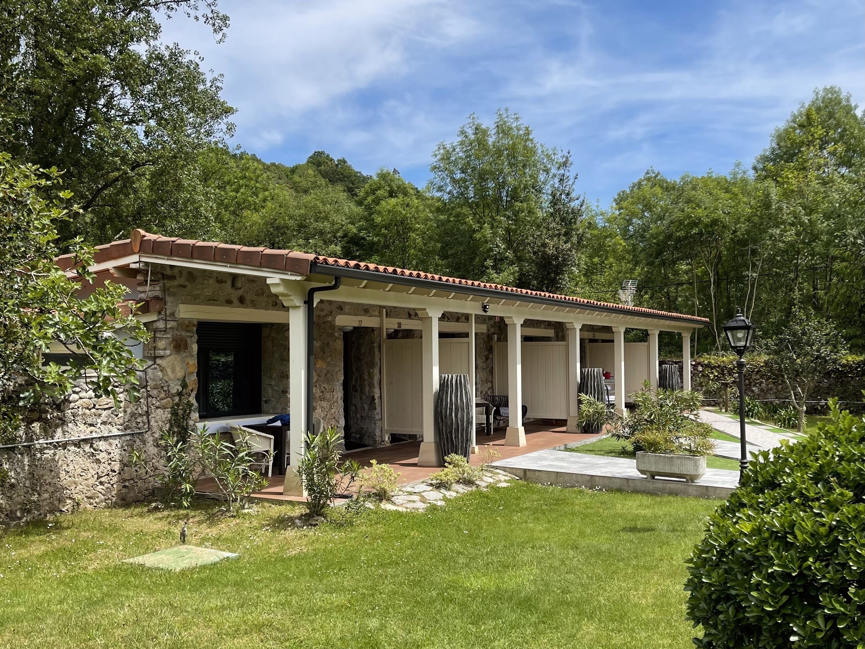 A stone building with a tiled roof and a covered patio area.