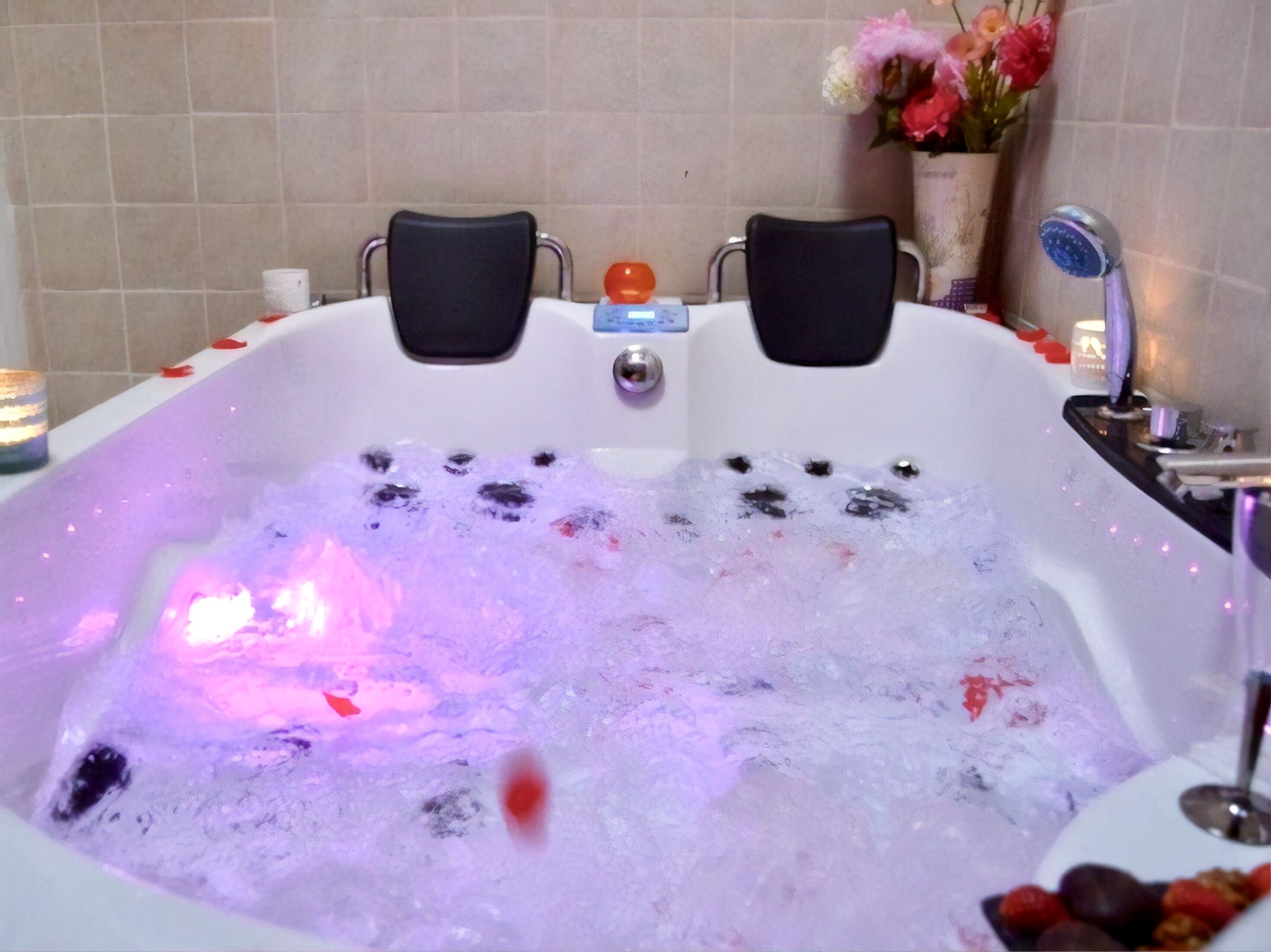 Et badekar fyldt med bobler og et vandmassage system, med to sorte stole foran.